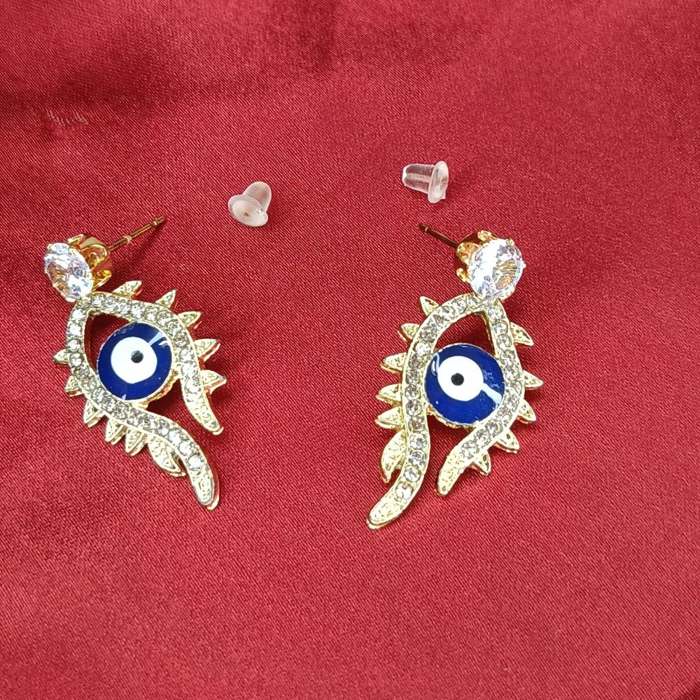 Close-up of gold-tone evil eye earrings with sparkling crystal embellishments on a red background