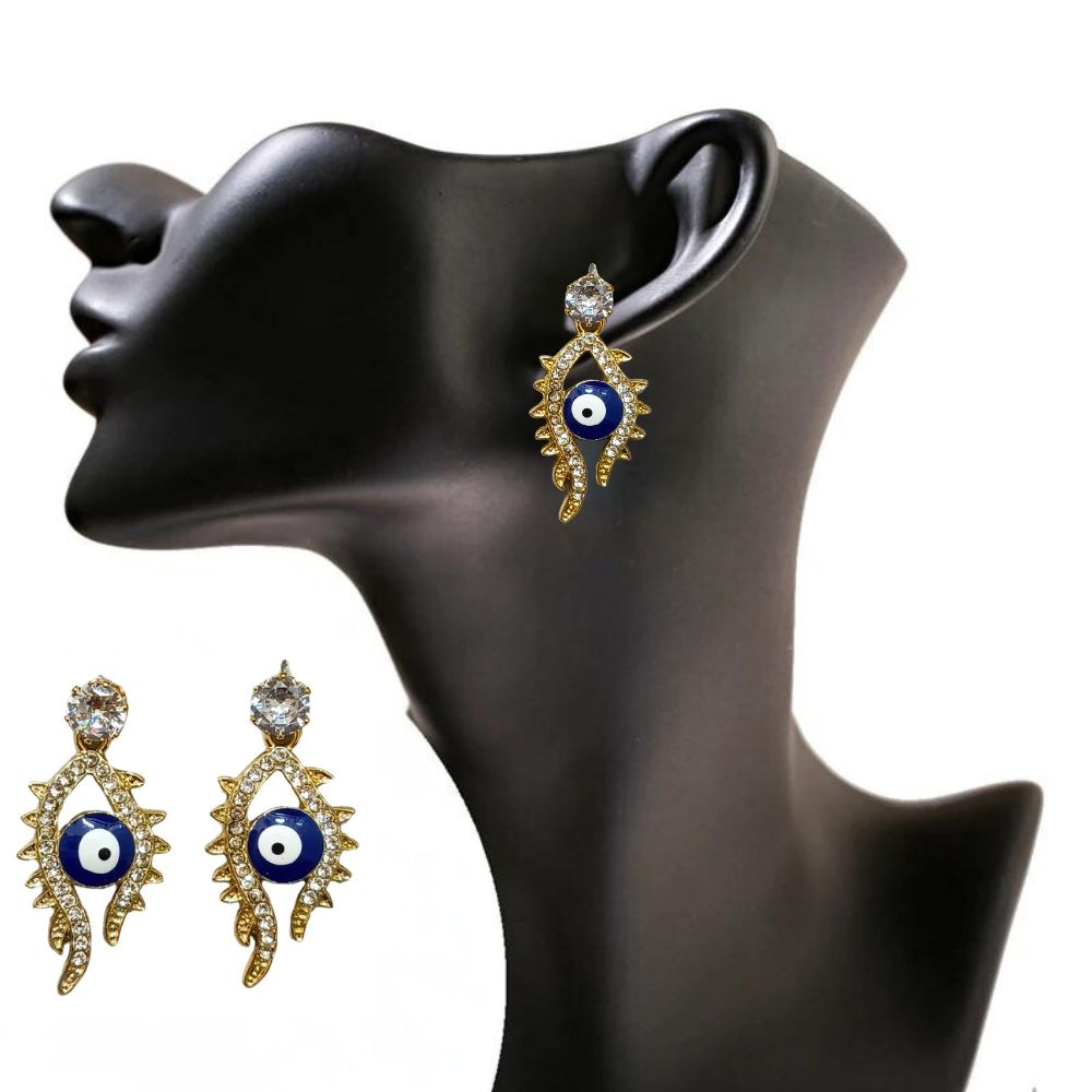 Close-up of gold-tone evil eye earrings with sparkling crystal embellishments on a red background