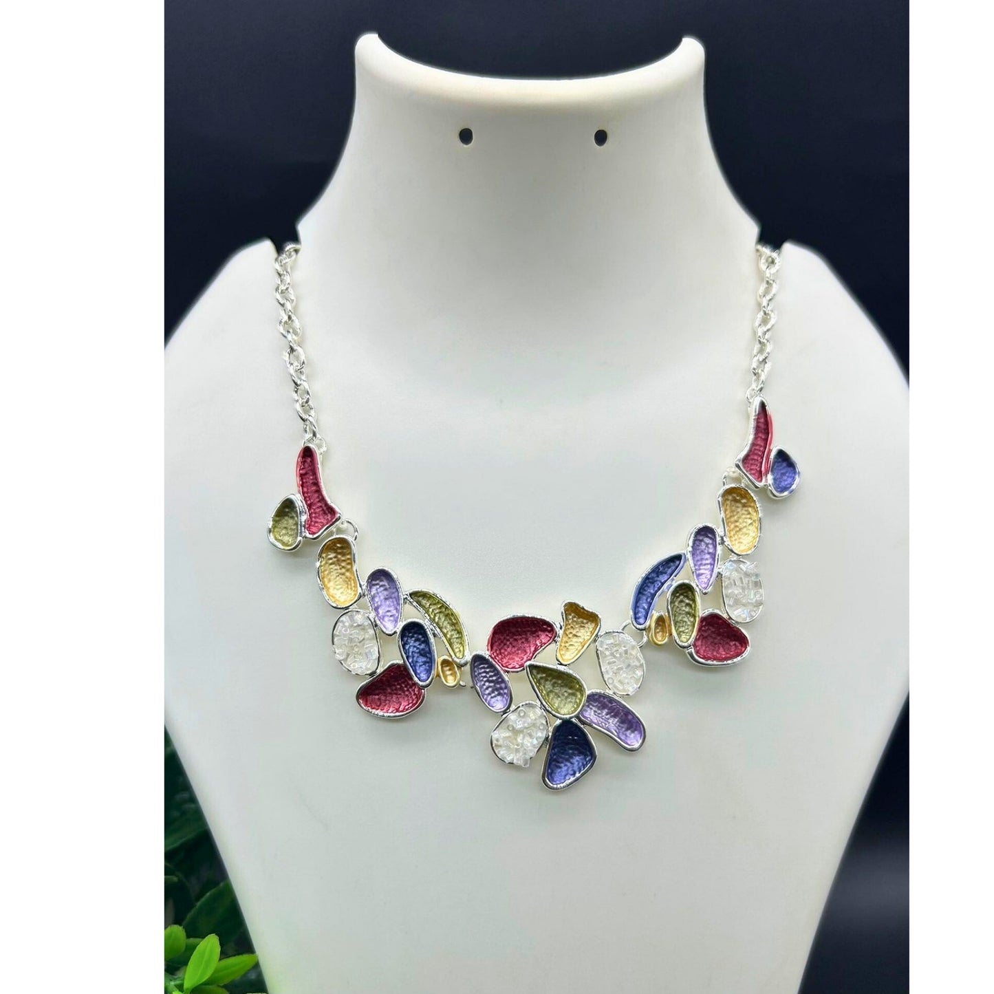 A vibrant multicolor statement necklace with purple, gold, red, and green enamel accents on an adjustable silver-tone chain