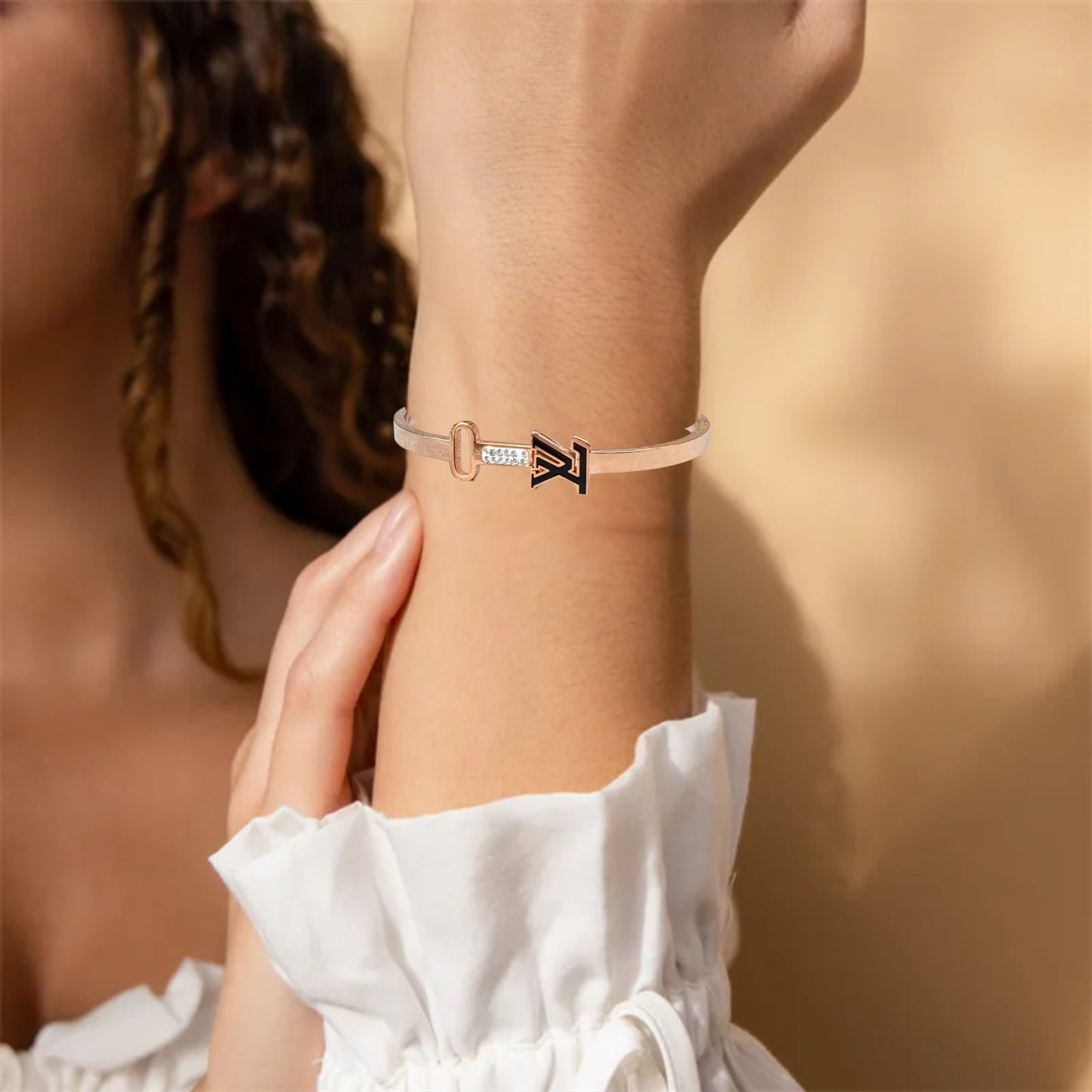 Close-up of a rose gold bracelet featuring a sleek key and initial design, with sparkling accents, perfect for stylish women.
