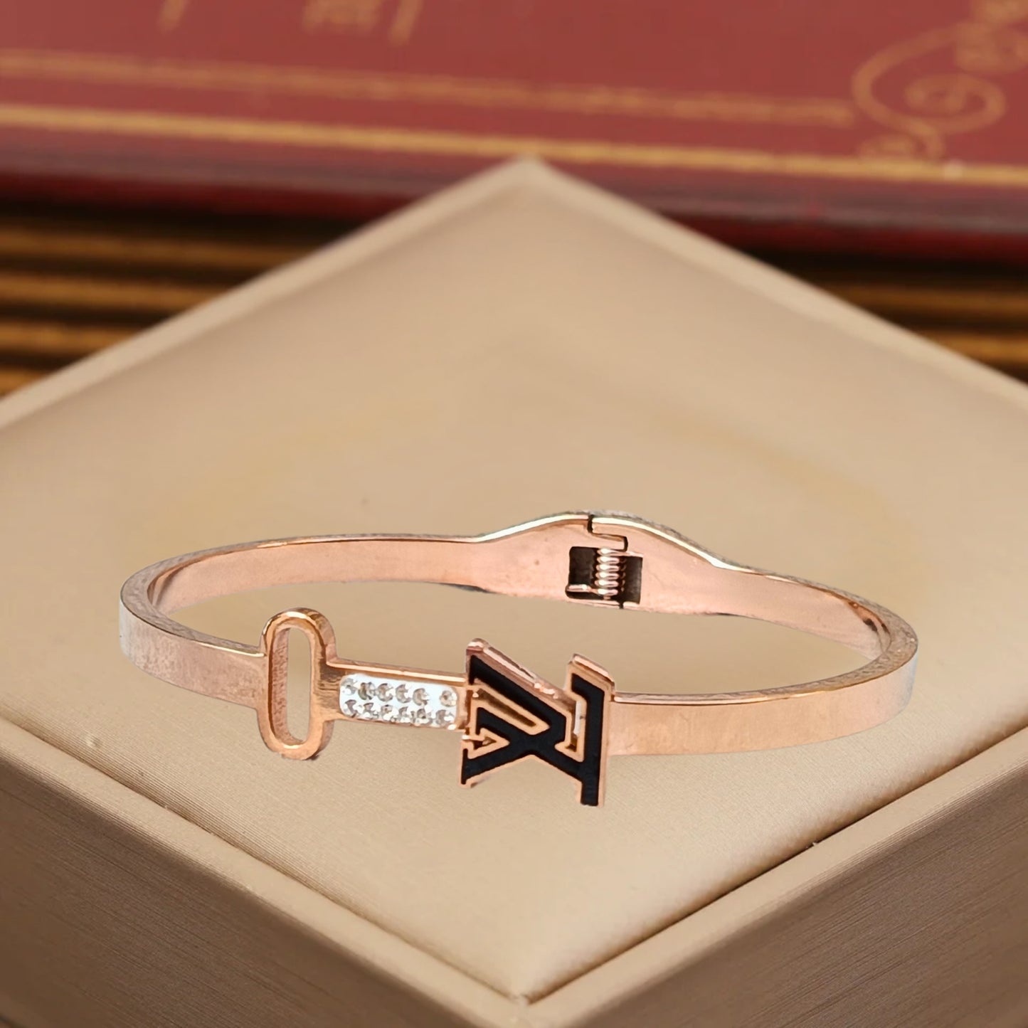 Close-up of a rose gold bracelet featuring a sleek key and initial design, with sparkling accents, perfect for stylish women.