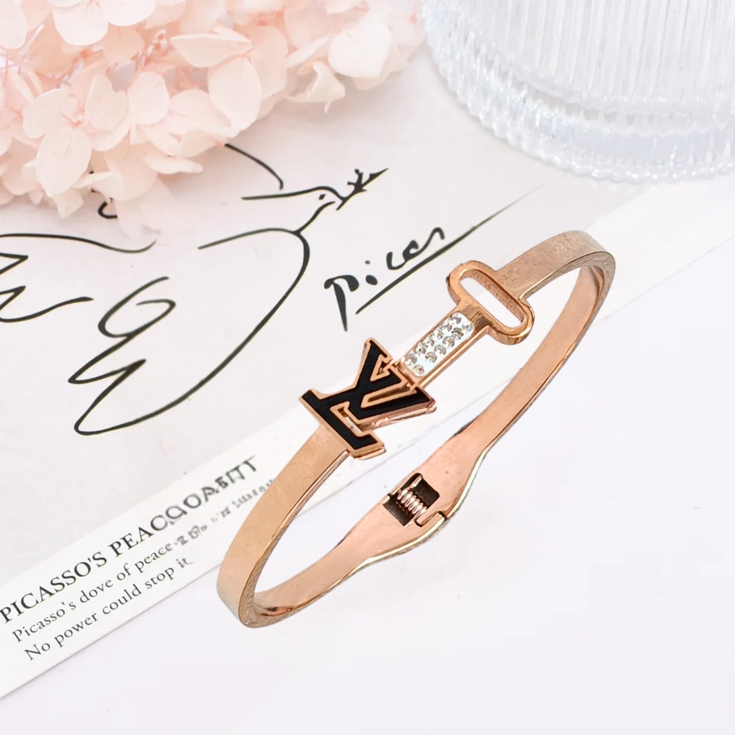 Close-up of a rose gold bracelet featuring a sleek key and initial design, with sparkling accents, perfect for stylish women.