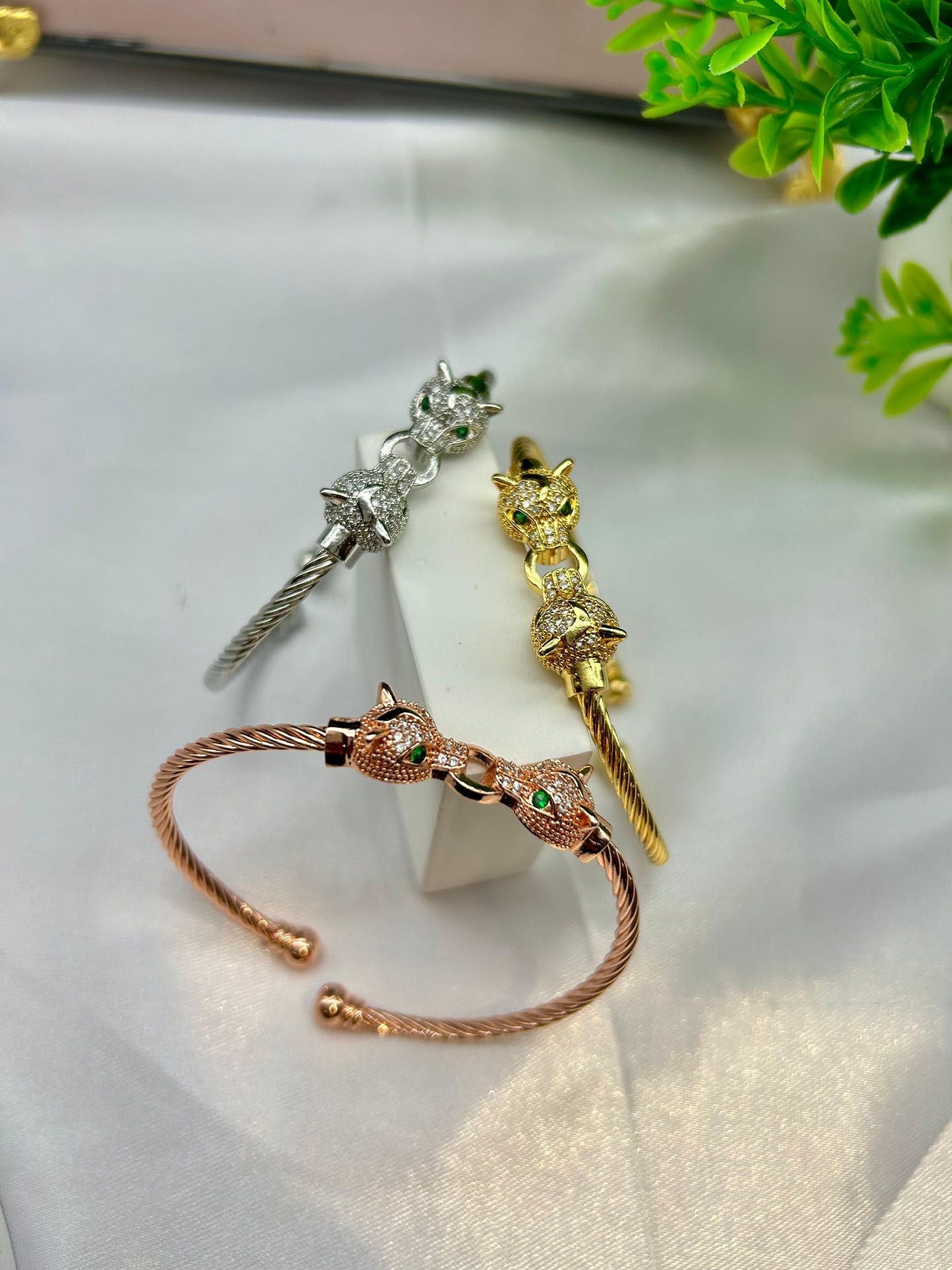 A rose gold cuff bracelet featuring two detailed jaguar heads with emerald-green eyes