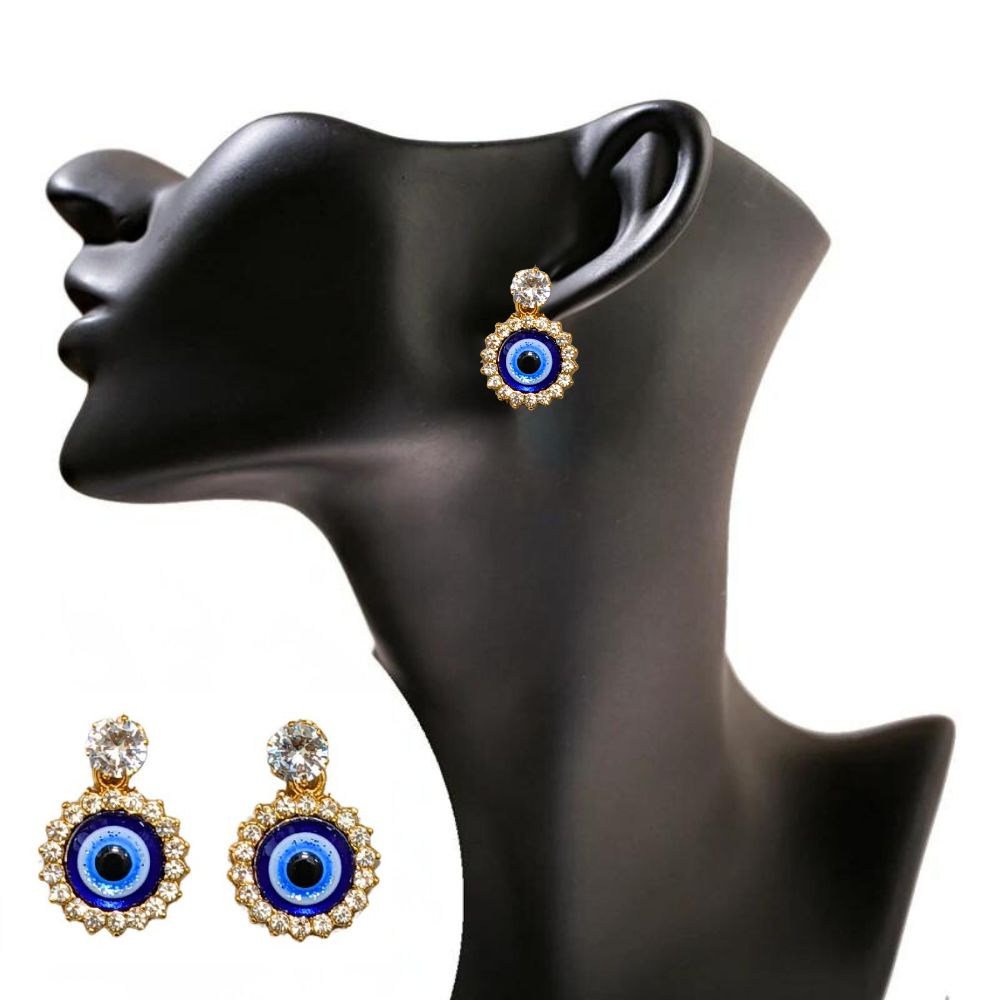 Close-up of gold evil eye earrings with a crystal halo design on a vibrant red fabric background
