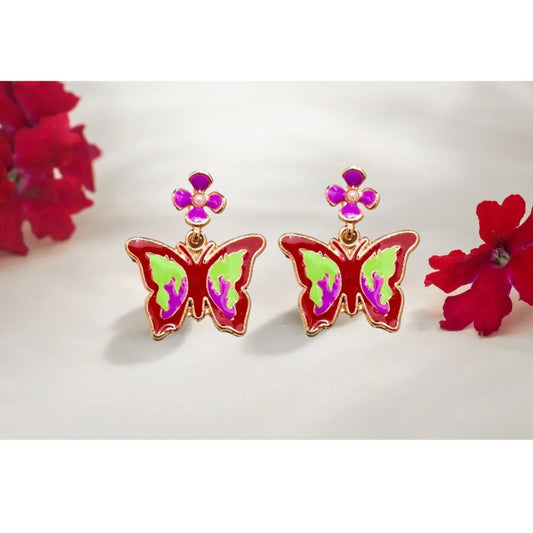Close-up of colorful butterfly earrings with red, green, and pink enamel, accented by purple flower studs